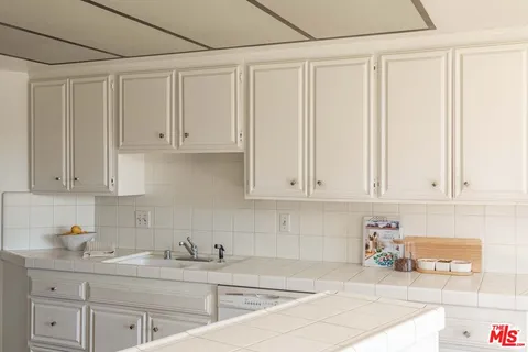 a kitchen with stainless steel appliances granite countertop a sink a stove and white cabinets