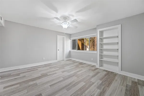 a view of an empty room with a window and wooden floor