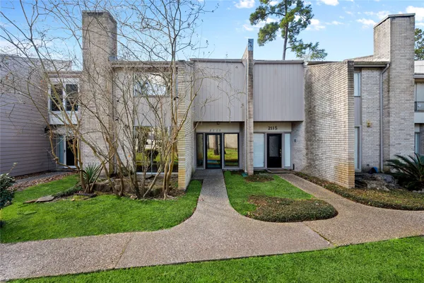 a view of a big house with brick walls plants and large tree