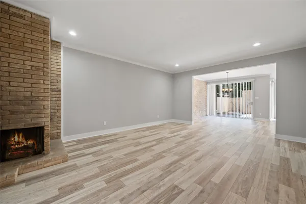 a view of an empty room with wooden floor fireplace and a window