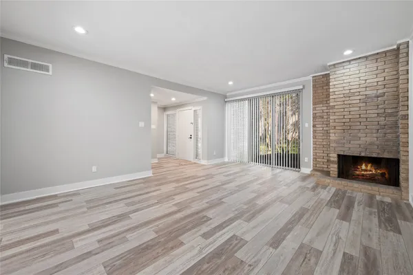 a view of an empty room with wooden floor fireplace and a window