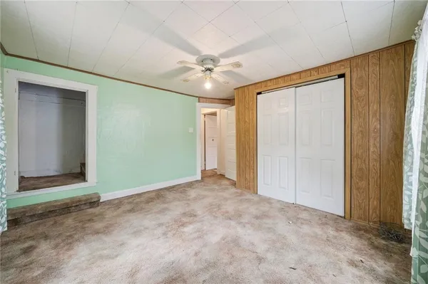 an empty room with closet and a chandelier fan