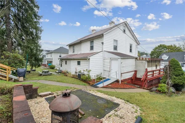 a view of a white house with a yard table and chairs