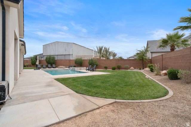 2278 Tawny Ridge Circle St. George, UT 84790 - Photo 59 of 61 Expansive backyard featuring a rectangular swimming pool with integrated spa, a concrete patio surround, a manicured lawn area, and decorative gravel landscaping.