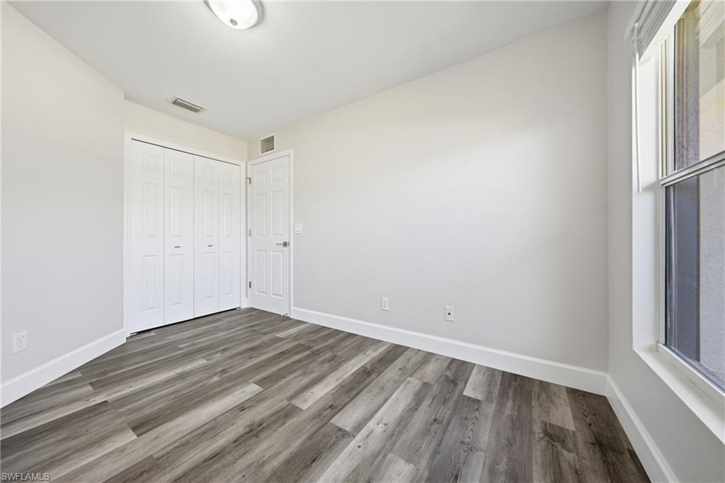4621 25th Street Southwest Lehigh Acres, FL 33973 - Photo 19 of 41 a view of an empty room with wooden floor and a window