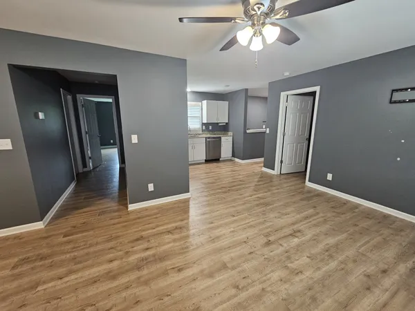 a view of a livingroom with a chandelier fan and wooden floor