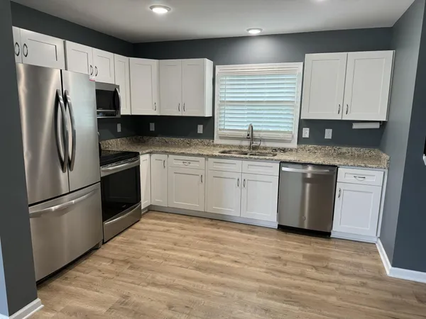 a kitchen with a sink stainless steel appliances and white cabinets