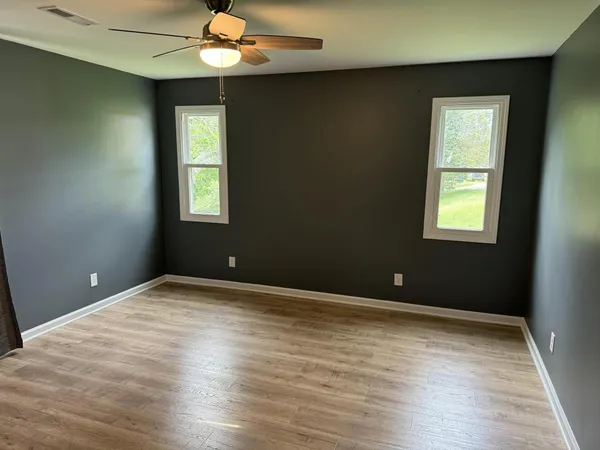 a view of an empty room with window and wooden floor