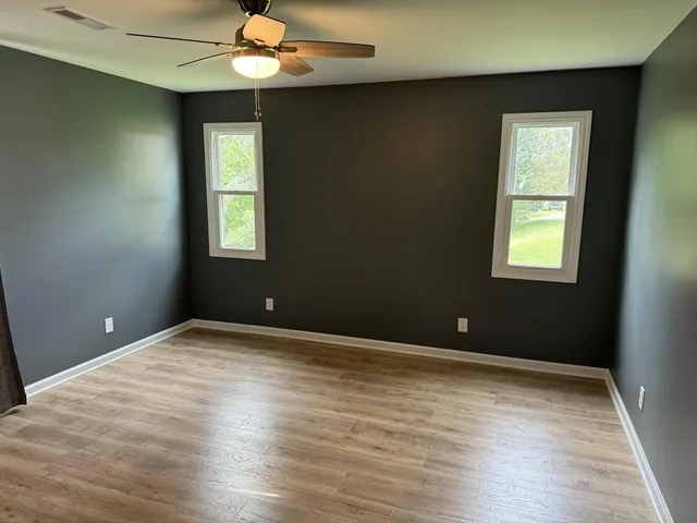 a view of an empty room with window and wooden floor