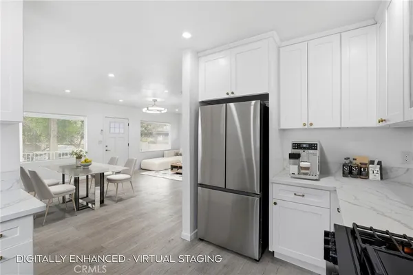 a kitchen with stainless steel appliances a refrigerator a stove a dining table and chairs with wooden floor