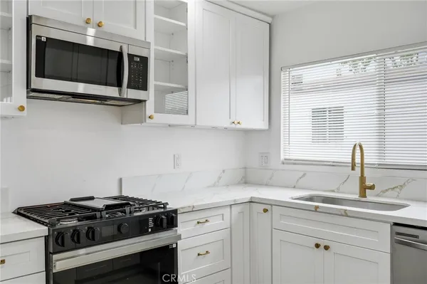 a kitchen with stainless steel appliances granite countertop white cabinets and a stove top oven