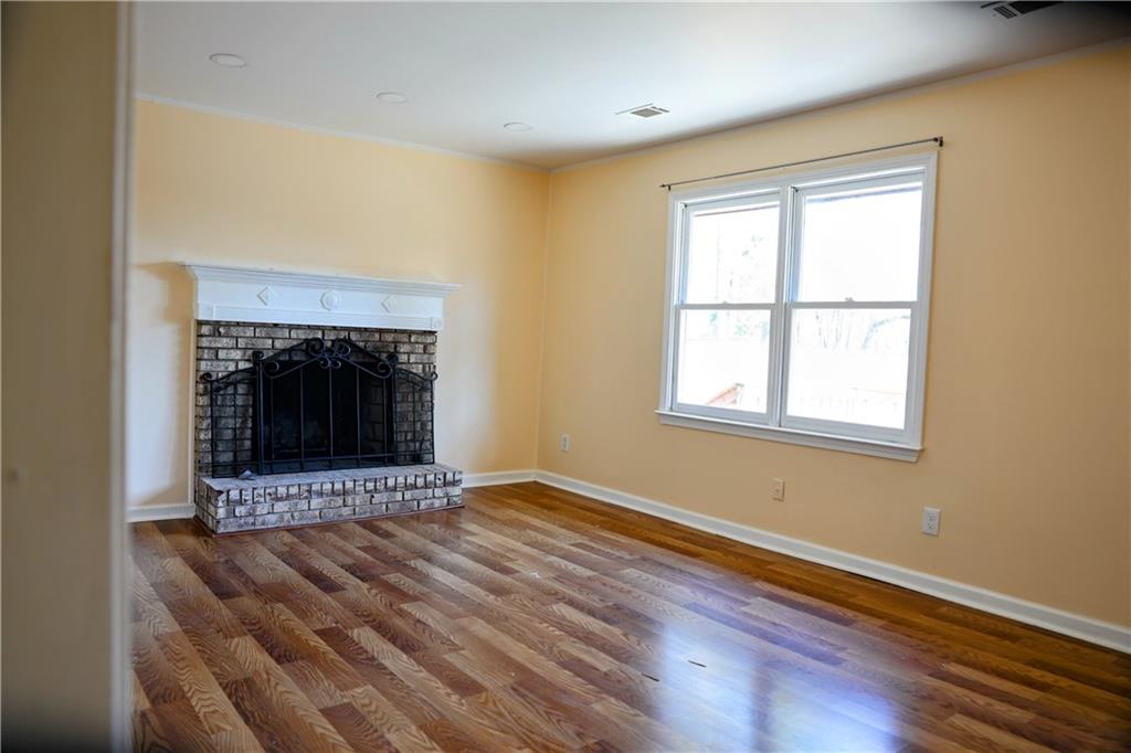 4296 Linda Lane Southwest Lilburn, GA 30047 - Photo 17 of 29 a view of an empty room with wooden floor fireplace and a window