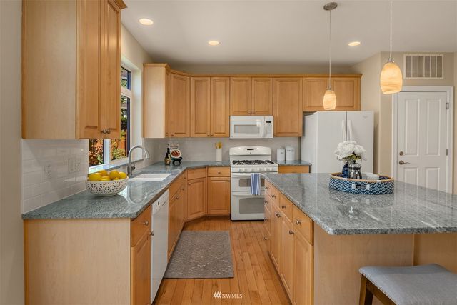 a kitchen with stainless steel appliances granite countertop sink stove refrigerator and cabinets
