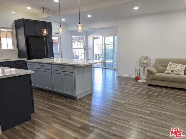 a large kitchen with kitchen island a sink dishwasher a dining table and chairs with wooden floor