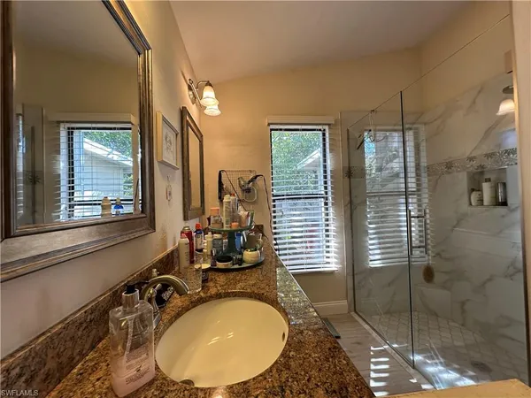 a bathroom with a granite countertop sink a mirror and shower
