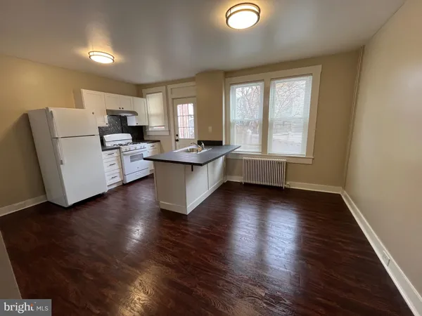 a living room with hard wood floors and a kitchen
