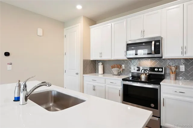 a kitchen with granite countertop a sink a stove and cabinets