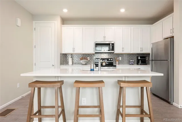 a kitchen with stainless steel appliances granite countertop a white cabinets and a refrigerator