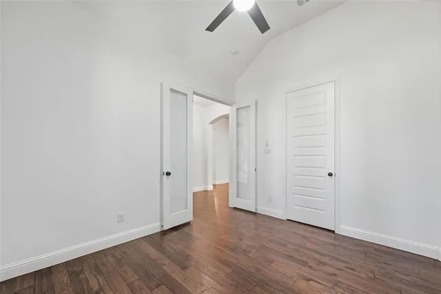 an empty room with wooden floor and ceiling fan