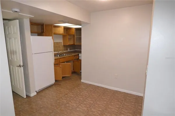 a view of a refrigerator in kitchen and an empty room