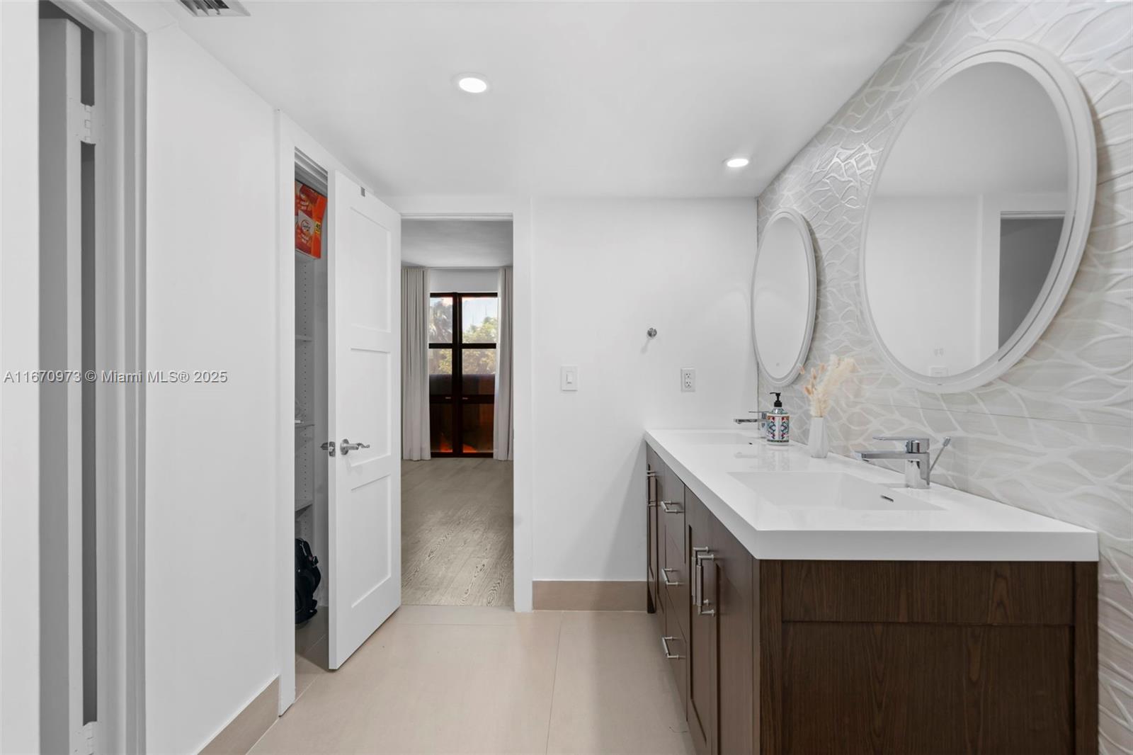 1121 Crandon Boulevard, Unit E105 Key Biscayne, FL 33149 - Photo 18 of 43 a en suite bathroom with a double vanity sink and a mirror