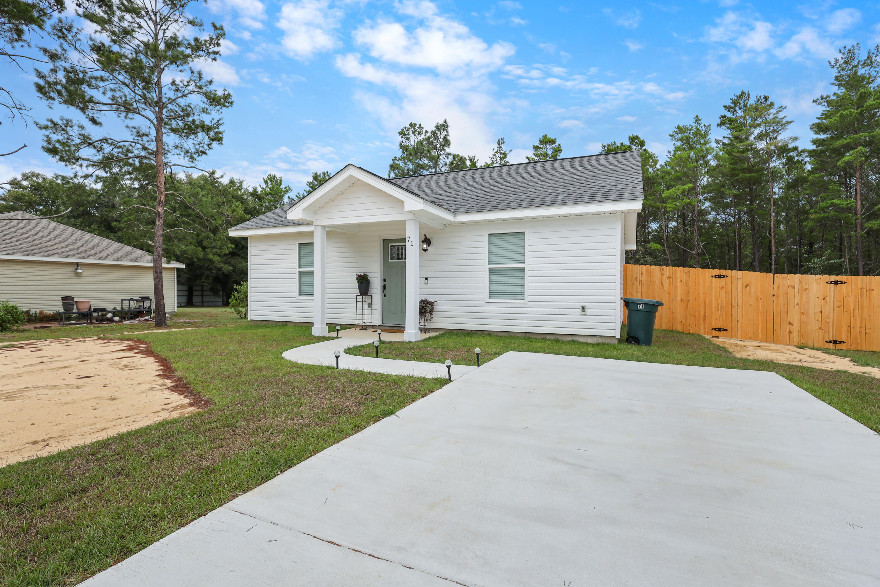 71 Lafavre Lane DeFuniak Springs, FL 32433 - Photo 27 of 32 a view of a white house with a yard plants and large tree