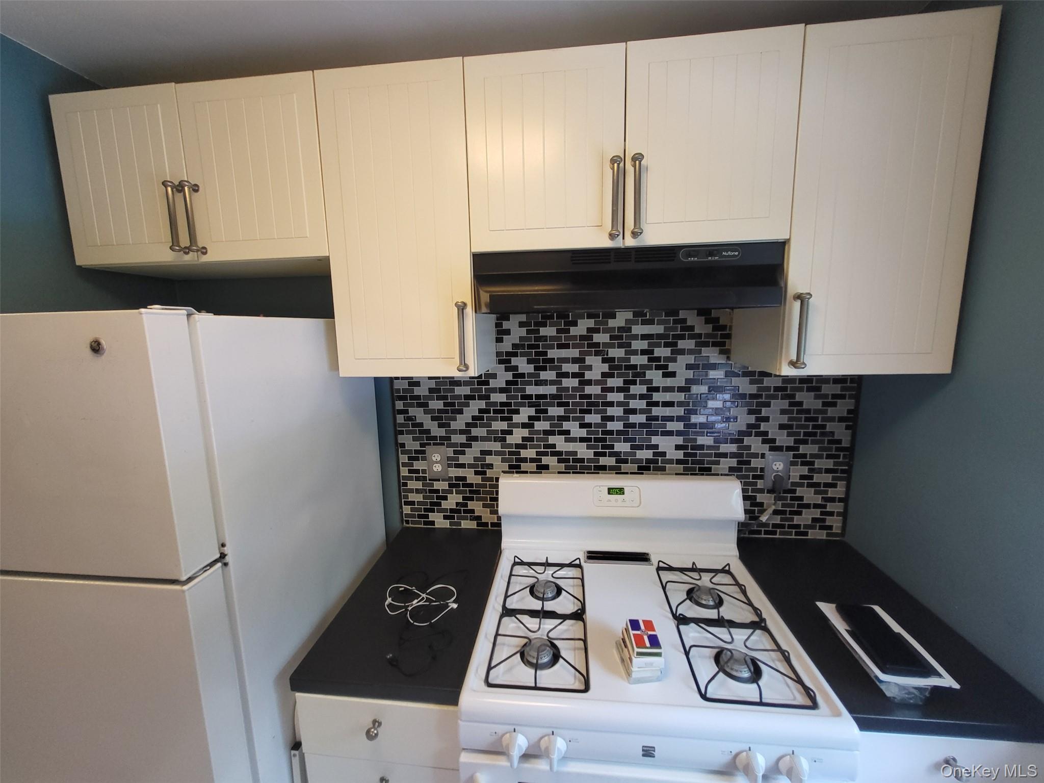 224-23 Kingsbury Avenue, Unit B Queens, NY 11364 - Photo 17 of 22 Kitchen featuring white appliances, under cabinet range hood, and decorative backsplash