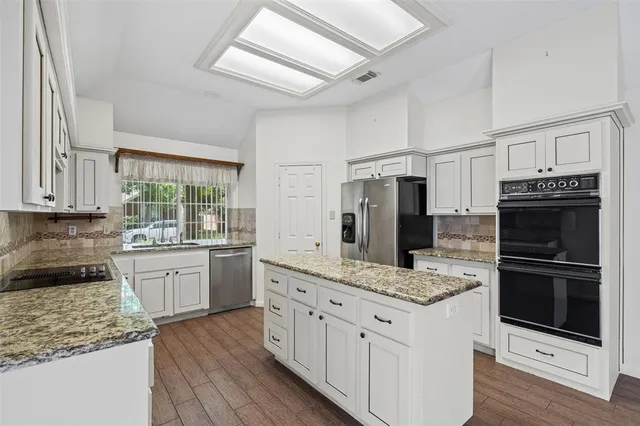 a kitchen with stainless steel appliances granite countertop a stove refrigerator and cabinets