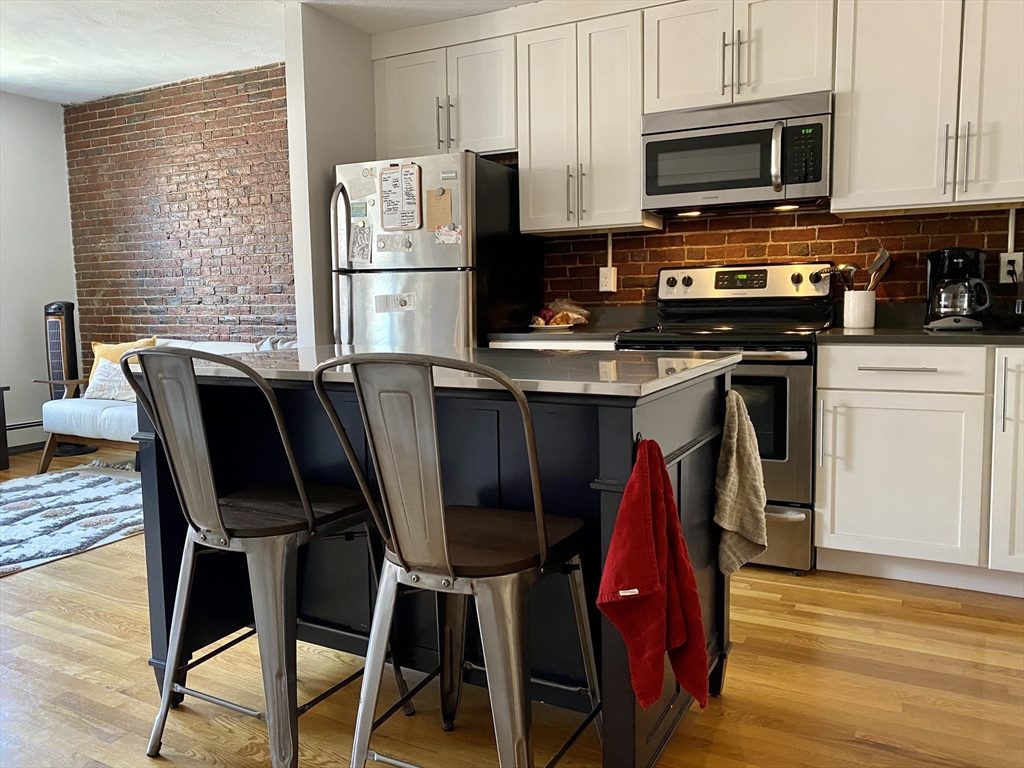 178 North Street, Unit 4 Boston, MA 02113 - Photo 1 of 8 a view of kitchen with stainless steel appliances granite countertop a stove top oven a refrigerator a dining table and chairs with wooden floor