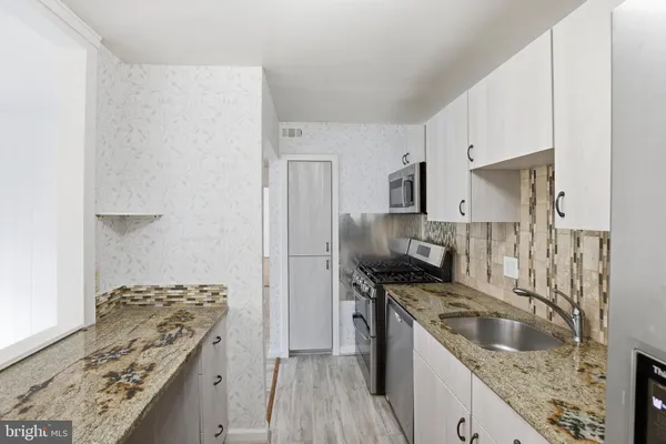a kitchen with stainless steel appliances granite countertop a sink stove and refrigerator