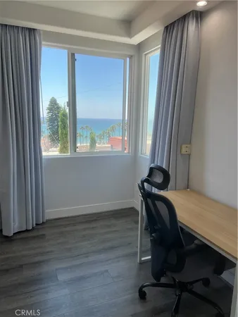 a view of a workspace with furniture and a window