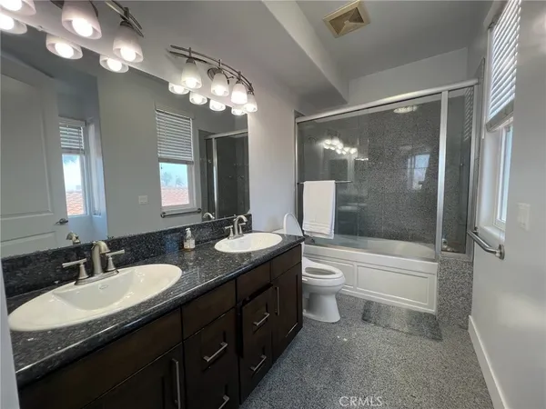 a bathroom with a granite countertop sink toilet a large mirror a bathtub and shower