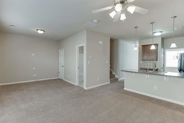 an empty room with a kitchen and a chandelier fan