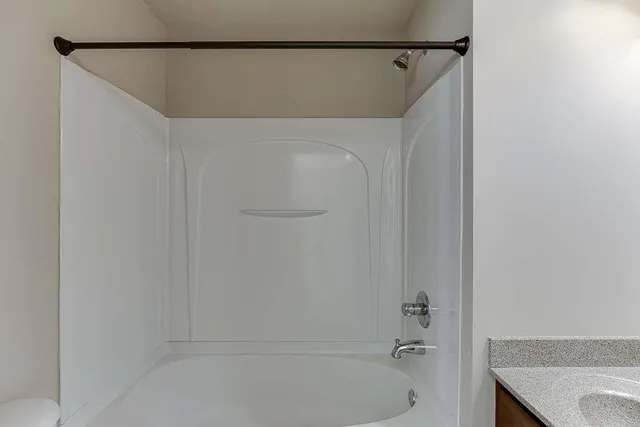 an empty room with a chandelier fan and windows