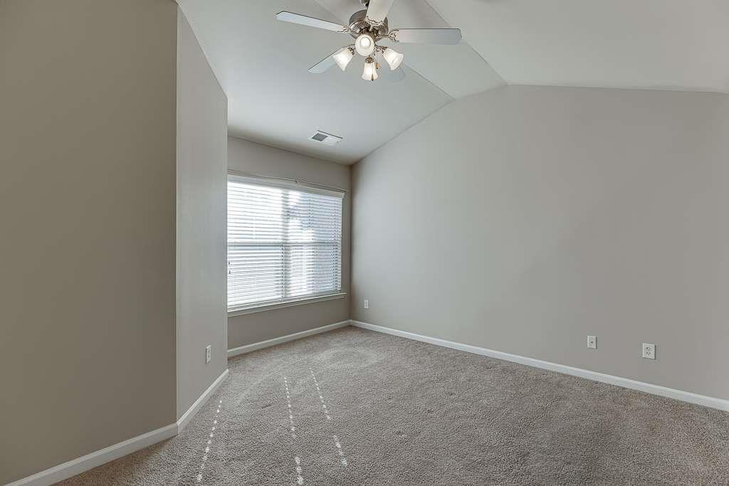 1043 Nightfall Court Northwest Suwanee, GA 30024 - Photo 23 of 39 an empty room with a chandelier fan and windows
