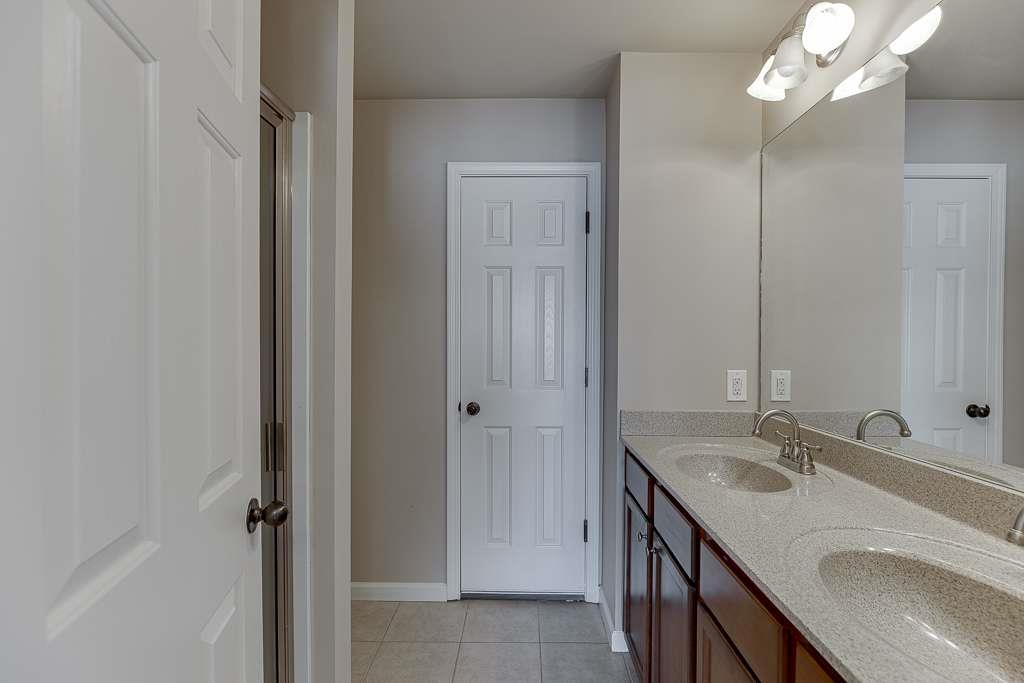 1043 Nightfall Court Northwest Suwanee, GA 30024 - Photo 27 of 39 a bathroom with a granite countertop sink a mirror and a shower