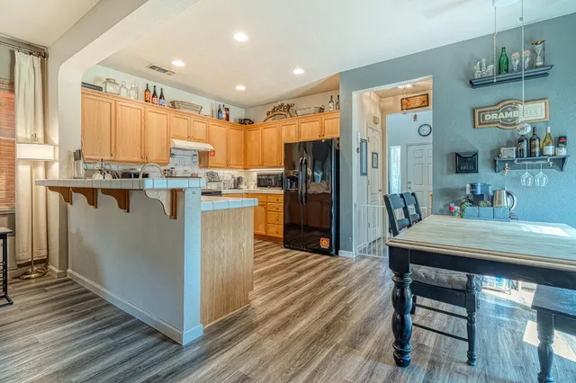 a kitchen with kitchen island a stove a refrigerator a dining table and chairs