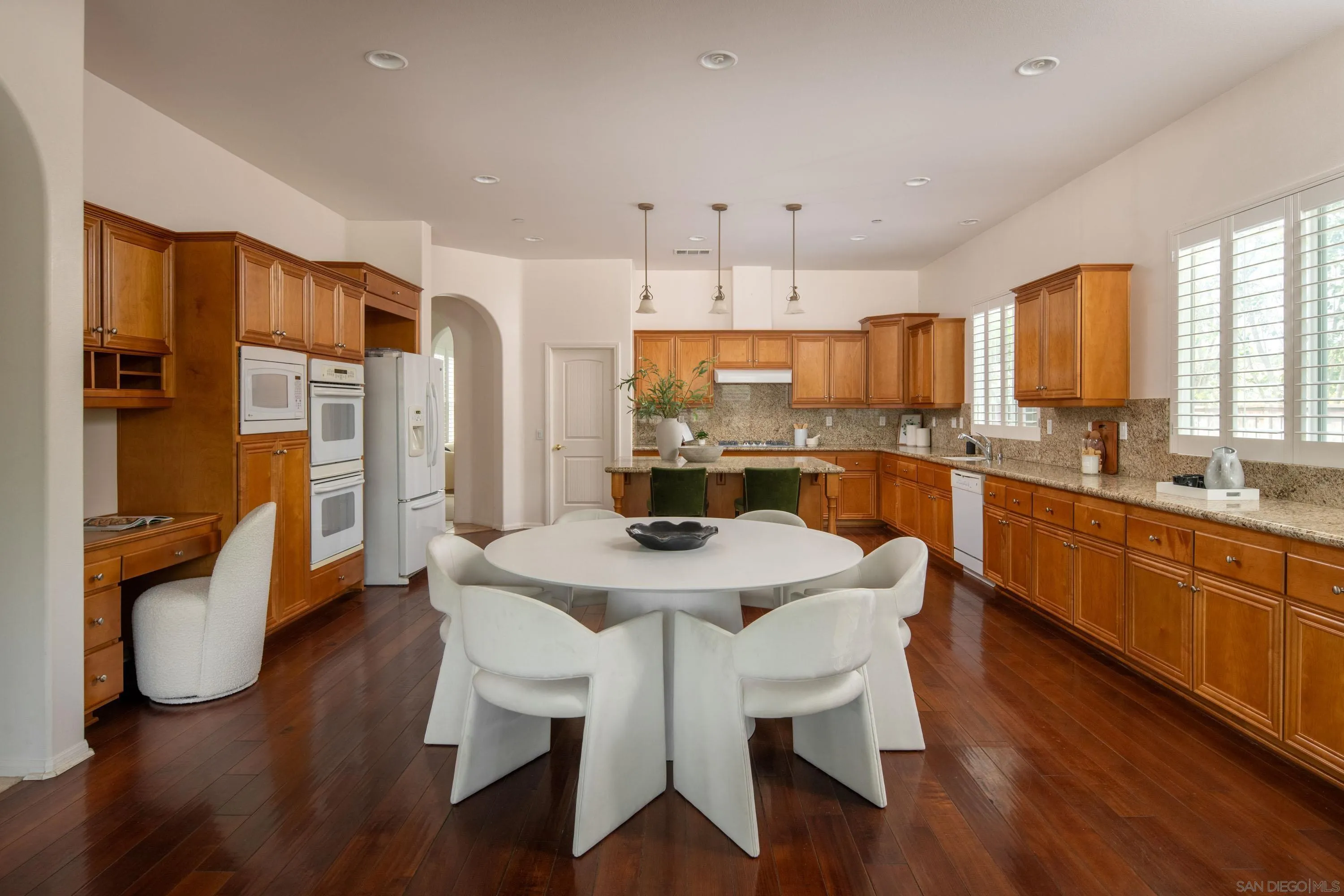14220 Pebble Beach Way Valley Center, CA 92082 - Photo 4 of 48 a kitchen with stainless steel appliances granite countertop a dining table chairs refrigerator sink and cabinets