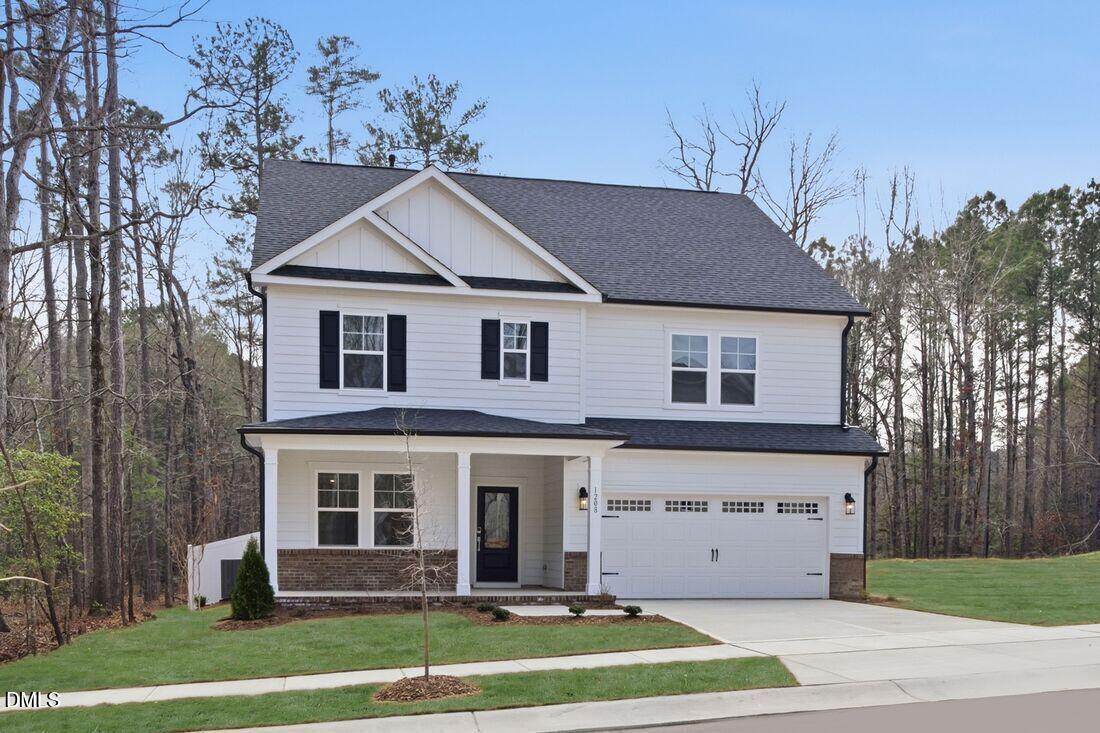1208 Condor Jct Road Wendell, NC 27591 - Photo 31 of 57 a view of a white house with large windows and a yard with plants and large trees