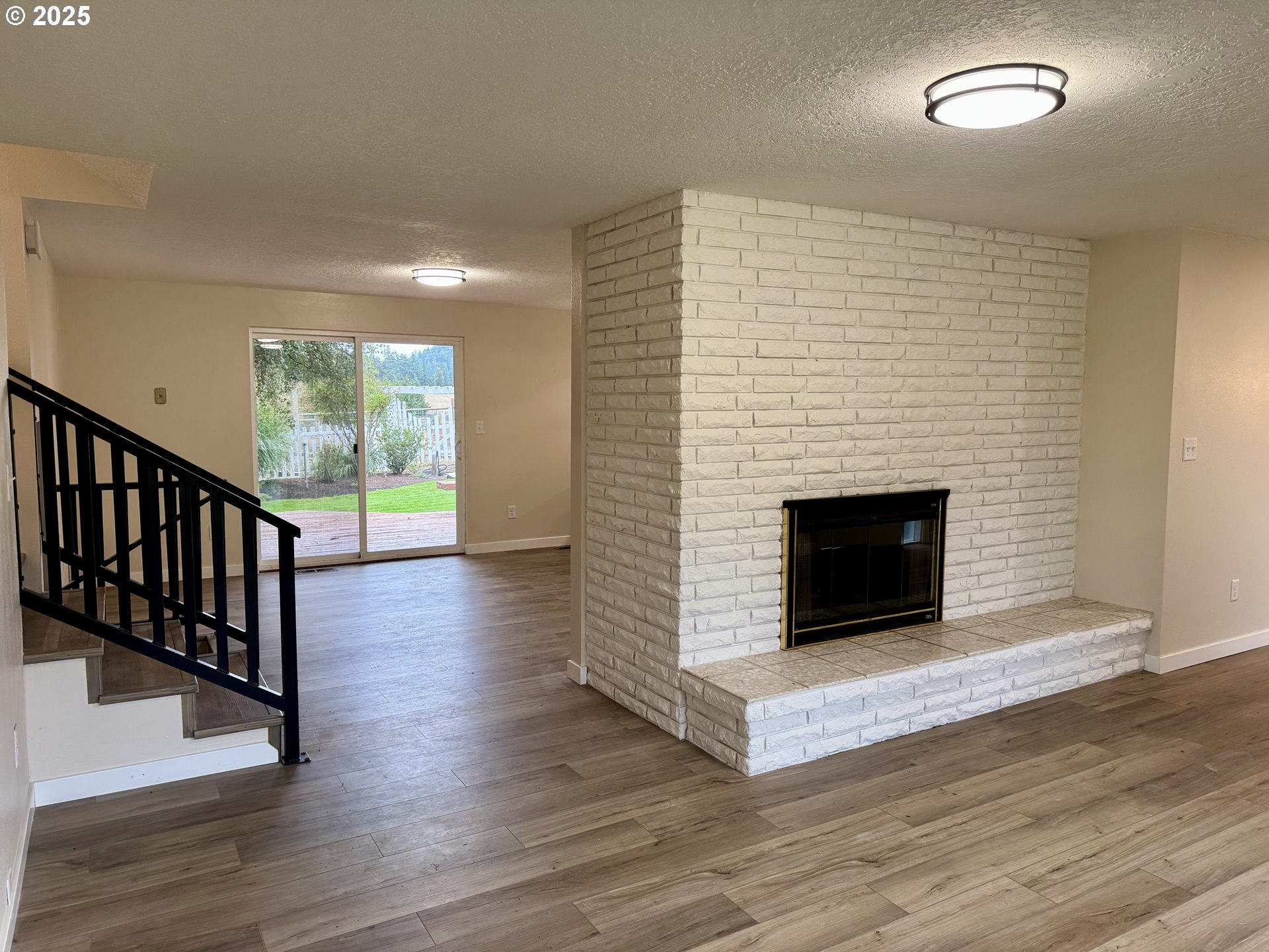 35929 Enterprise Road Creswell, OR 97426 - Photo 19 of 48 an empty room with wooden floor a fireplace and windows