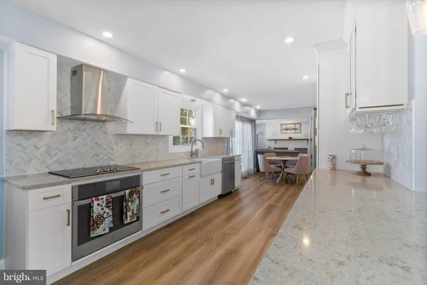a large white kitchen with lots of counter top space a sink stainless steel appliances and cabinets