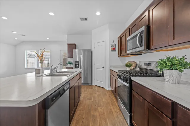 a kitchen with stainless steel appliances granite countertop a sink a stove and a refrigerator