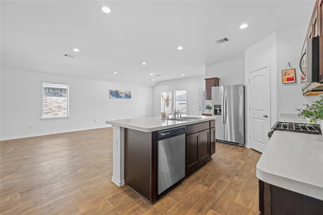 a kitchen with stainless steel appliances granite countertop a refrigerator a sink dishwasher a oven with white cabinets and wooden floor