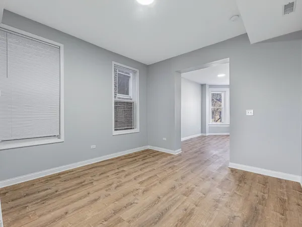 a view of an empty room with window and wooden floor