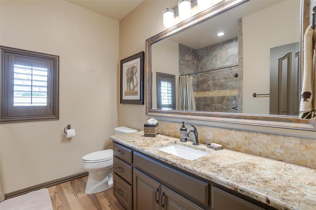 9310 Bellechase Road Granbury, TX 76049 - Photo 19 of 39 a bathroom with a granite countertop sink a toilet and a mirror