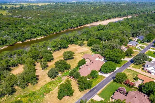 an aerial view of residential house with outdoor space and trees all around