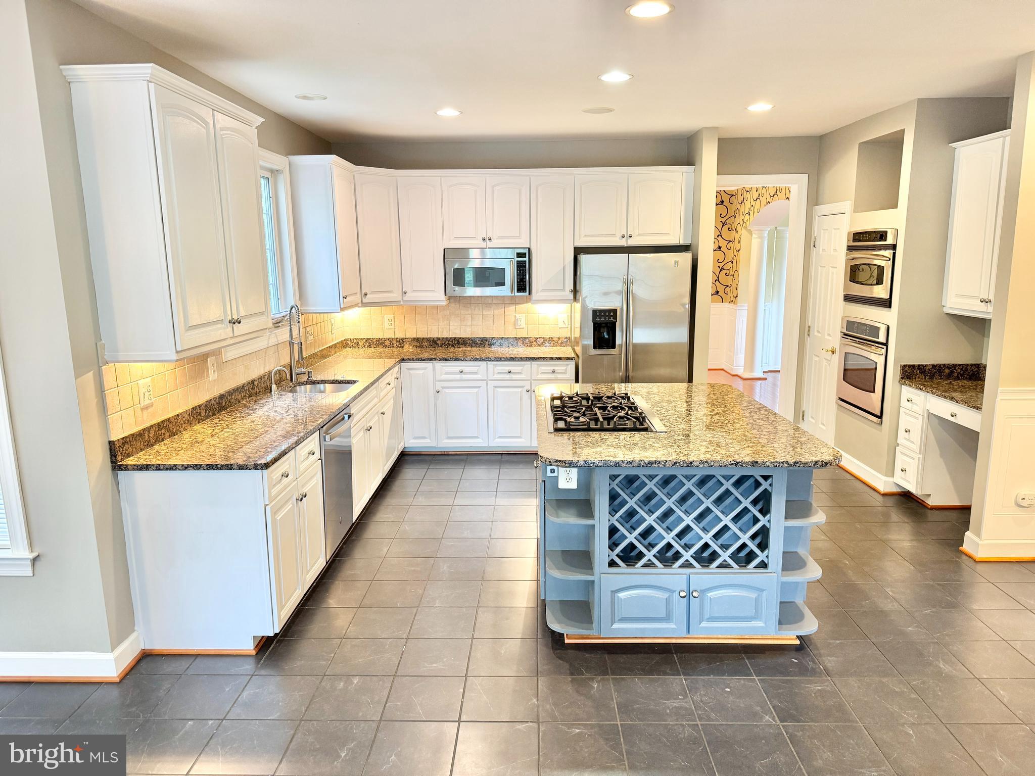 3500 Germainia Court Triangle, VA 22172 - Photo 3 of 77 a large kitchen with kitchen island granite countertop a stove a sink a refrigerator and white cabinets