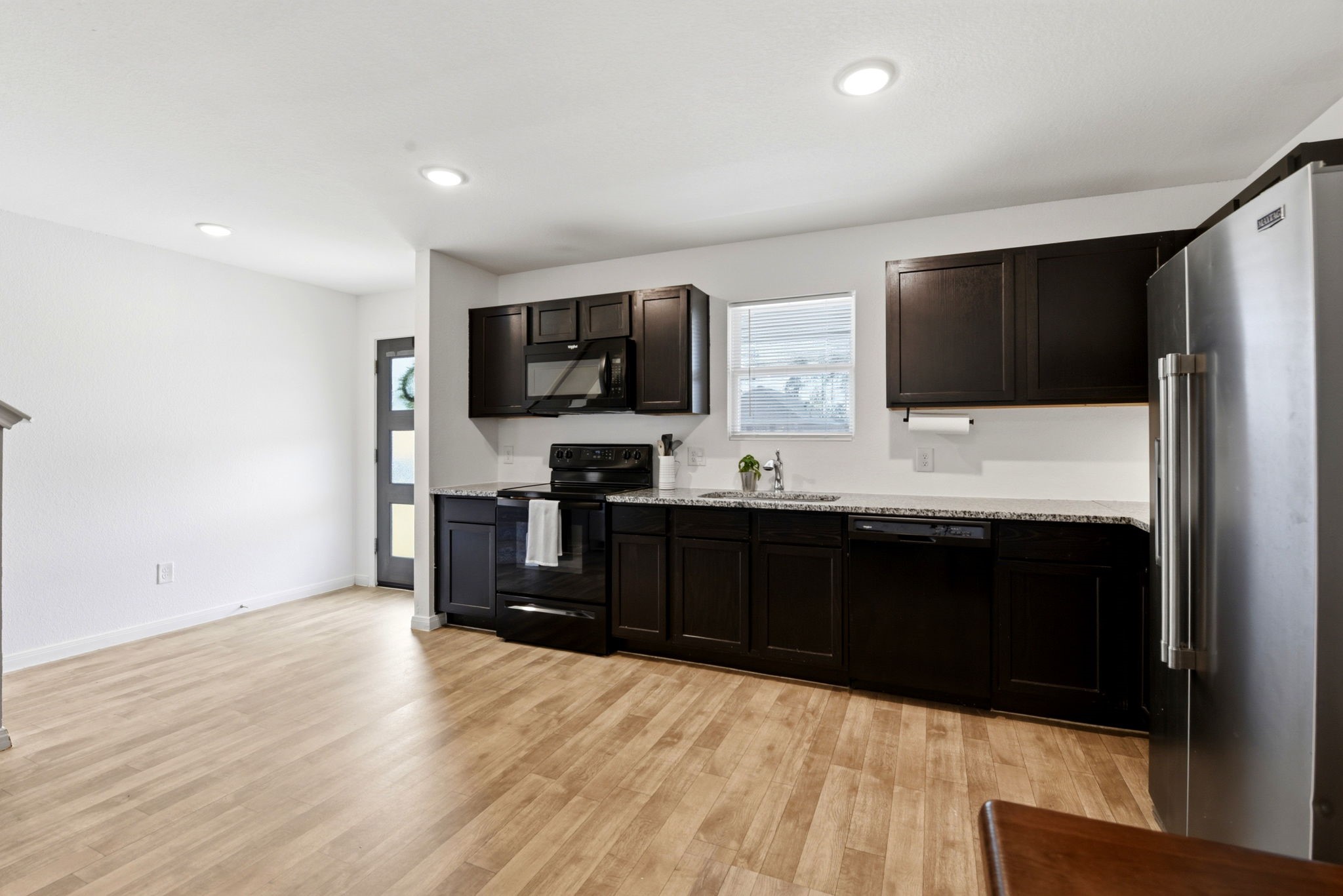 9819 Emerald Stone Way Conroe, TX 77306 - Photo 12 of 38 a living room with stainless steel appliances kitchen island granite countertop furniture a refrigerator and a flat screen tv