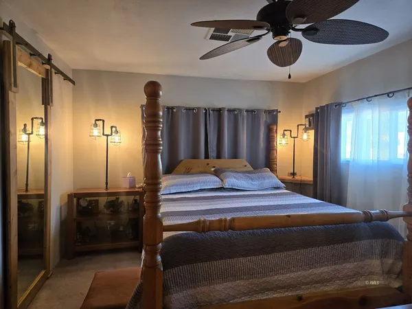 a bedroom with a bed a dresser and chandelier