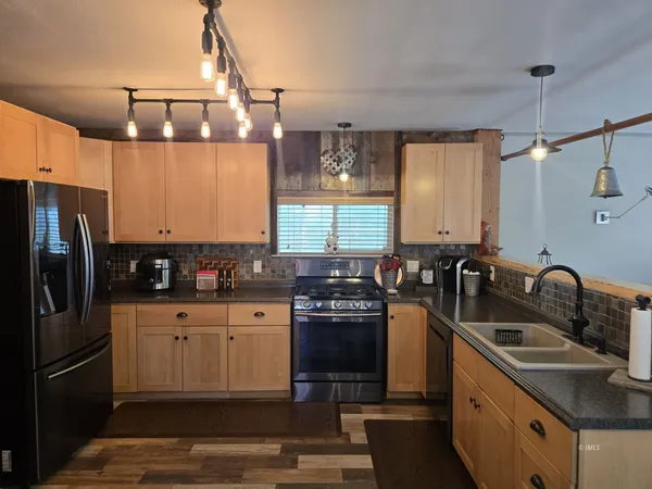 a kitchen with stainless steel appliances granite countertop a sink a stove and refrigerator